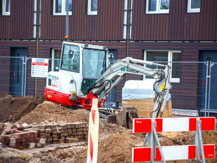 Mini-pelle et tranchée balisée par des barrières de chantier
